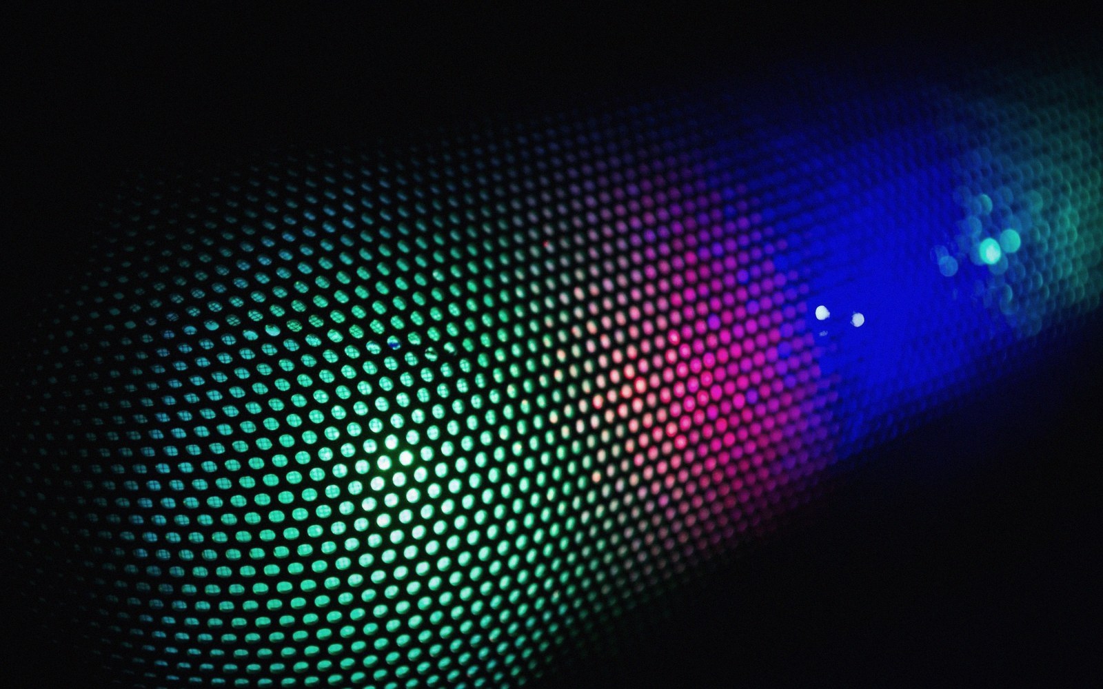 Colorful lights glowing through a perforated mesh screen in darkness